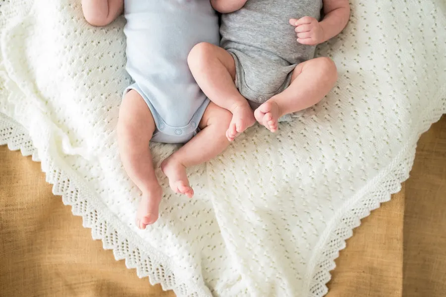 Ilustrasi mimpi bayi kembar — a couple of babies laying on top of a bed