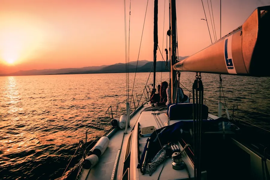 Ilustrasi mimpi berlayar — white and black sailboat during sunset
