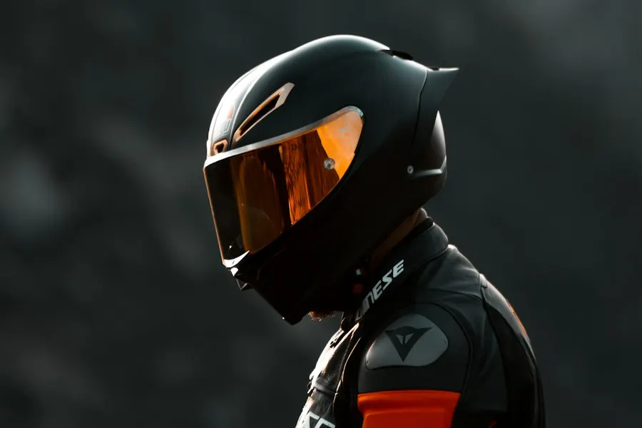 Ilustrasi mimpi helm — black and orange helmet on black motorcycle