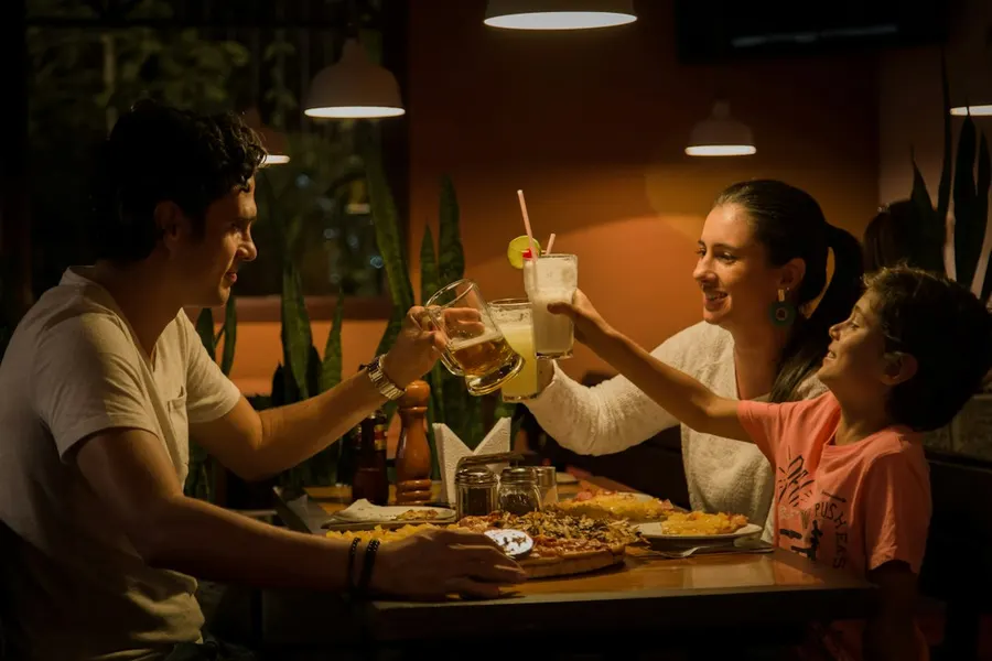 Ilustrasi mimpi makan bersama — three people having a toast on table