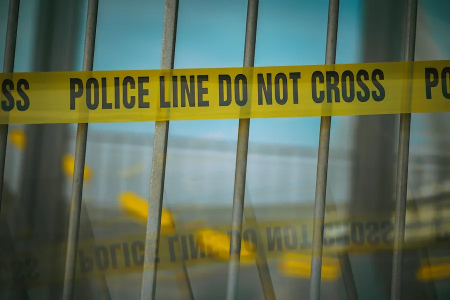 Ilustrasi mimpi melihat pembunuhan — a close up of a yellow police line behind bars