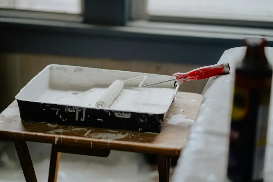 Ilustrasi mimpi renovasi rumah — A paint roller with a red handle in a tray of white paint