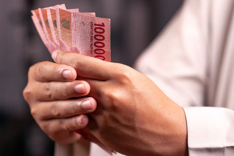 Ilustrasi mimpi uang kertas — Hands holding a stack of indonesian rupiah